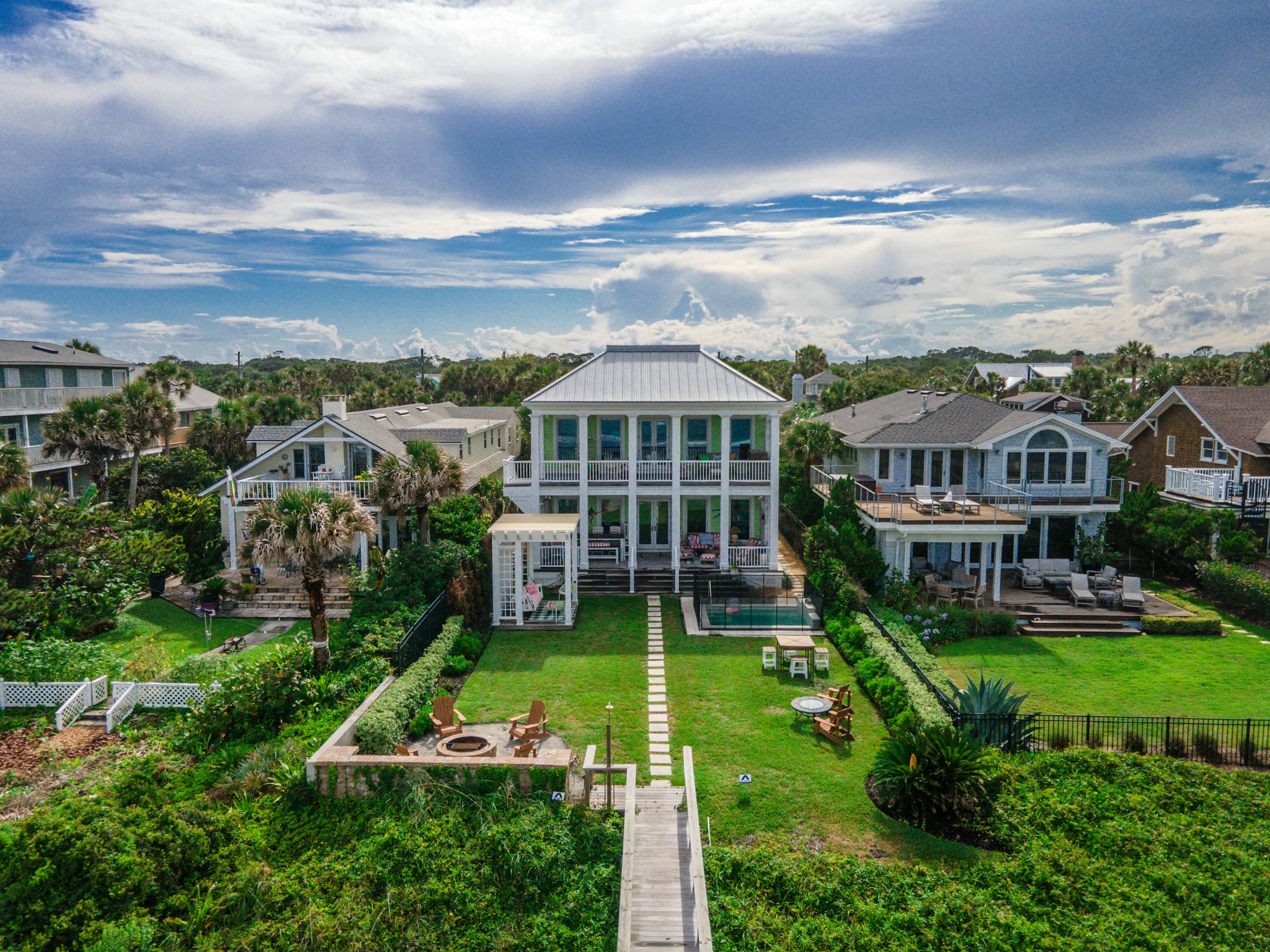 Aerial view of homes and gardens beneath a wide sky